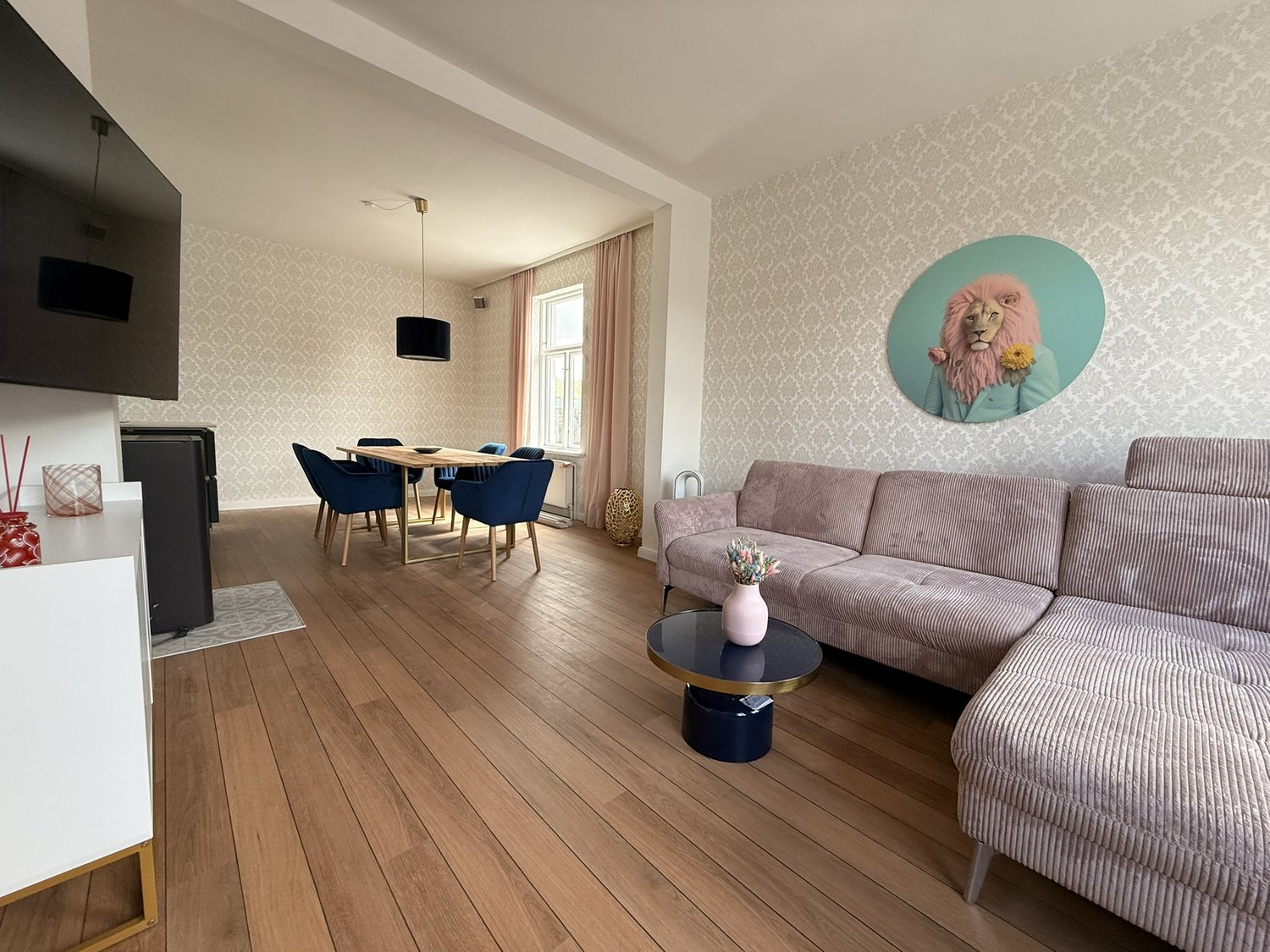 Wohn- und Essbereich mit Sofa, Esstisch und blauen Stühlen